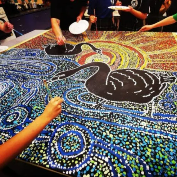 A group of young people are shown working on a community canvas art workshop hosted by Julianne Wade, local Whadjuk Nyoongar artist in Perth, Western Australia.