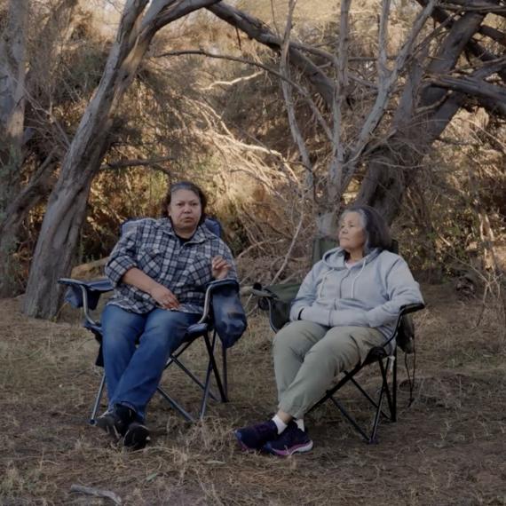 two people sit in outdoor chairs in the outdoors contemplating  