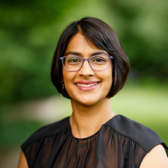 A person wearing glasses and a black top smiling at the camera