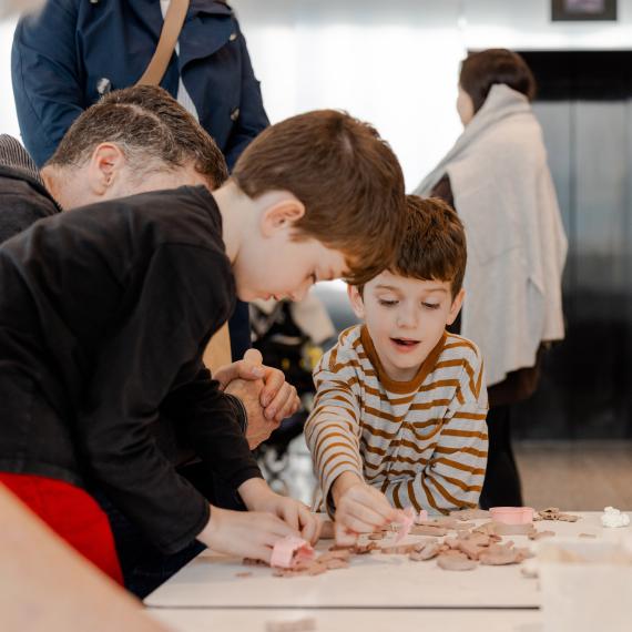 Two young boys gather around a table, happily shaping and playing with clay in a creative activity.