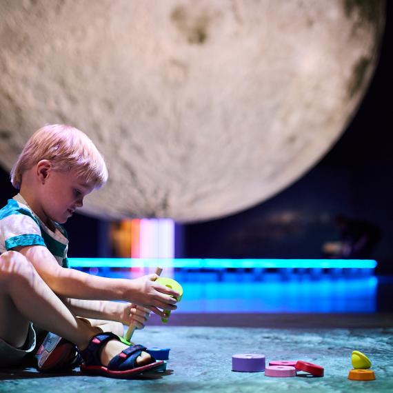 Toddler playing with blocks in front of large moon