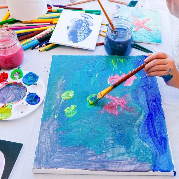 A Child painting a blue fish
