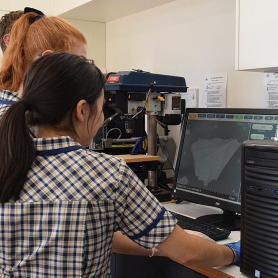 A group of school children looking at computer screen connect to a microscope
