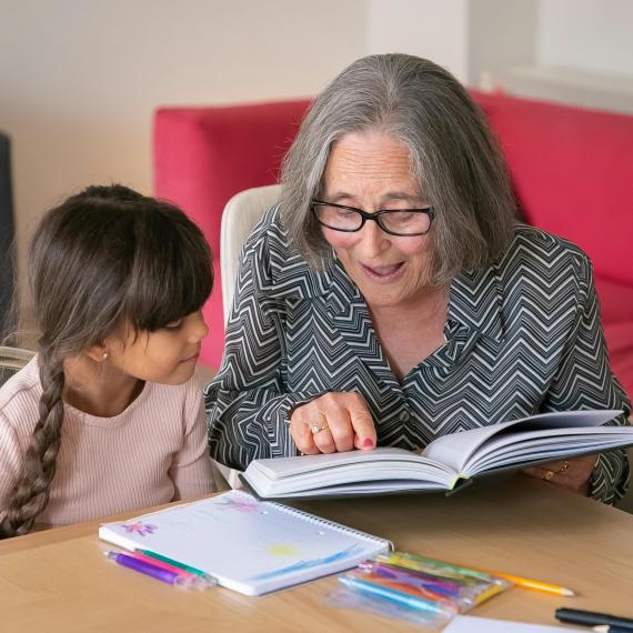 an older woman reads a book to a younger child