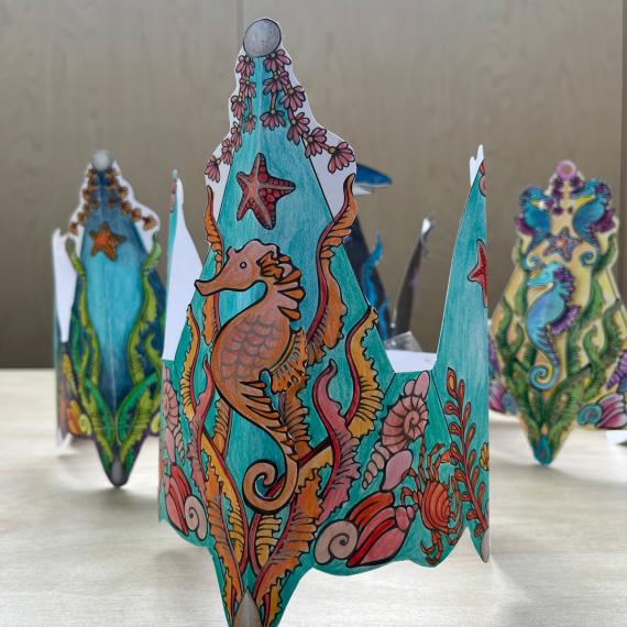 paper crowns with a sea scene decorated and coloured with pencils