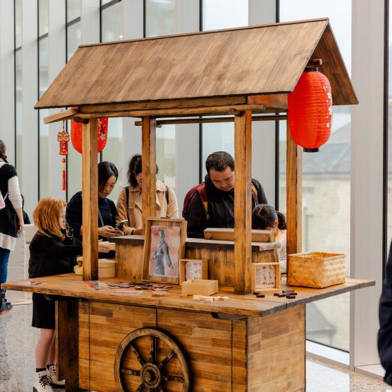 Group of people standing around a Chinese style cart looking down at activities