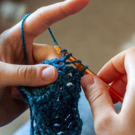 a close up of hands crocheting with yarn