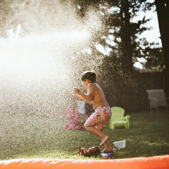 a child underneath th water spr