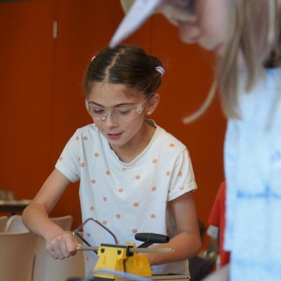Young child using clamp and wood working tools.