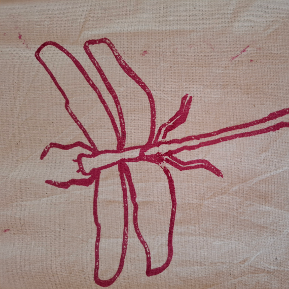 Red line drawing of a dragonfly on a beige textured fabric background.