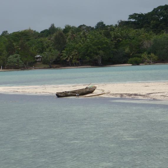 A traditional fishing boat with outrigger shown on a low-lying sandbar in Vanuatu.