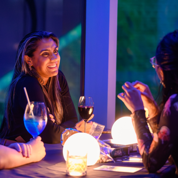 Two ladies having a conversation over a table with drinks.
