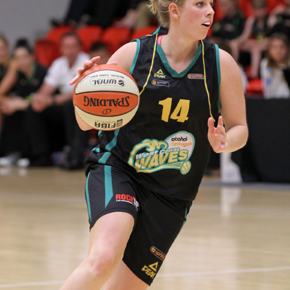 Basketball player, Melissa Marsh in a West Coast Waves uniform dribbling a ball on an indoor court.