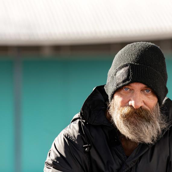 Man sitting look directly at the camera wearing a black beanie