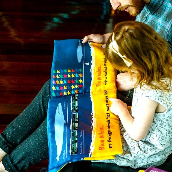 father reading to child in museum playspace about whales