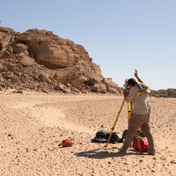 Landscape image of the Wadi el-Hudi Egyptian Desert. Researcher photographing rock formation.