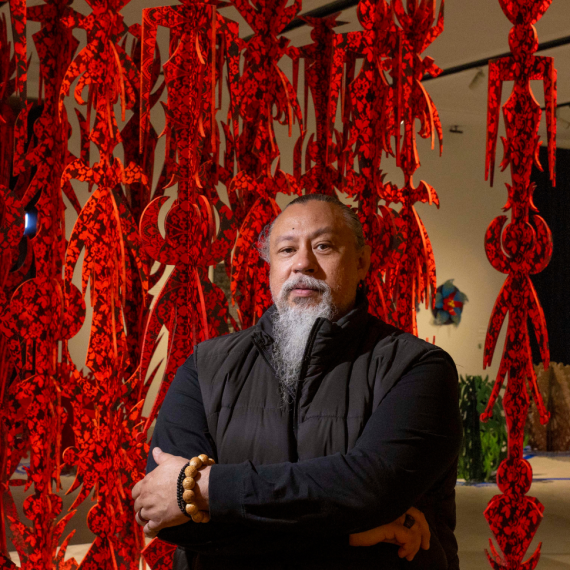 Man stands with his arms folded in front of artwork