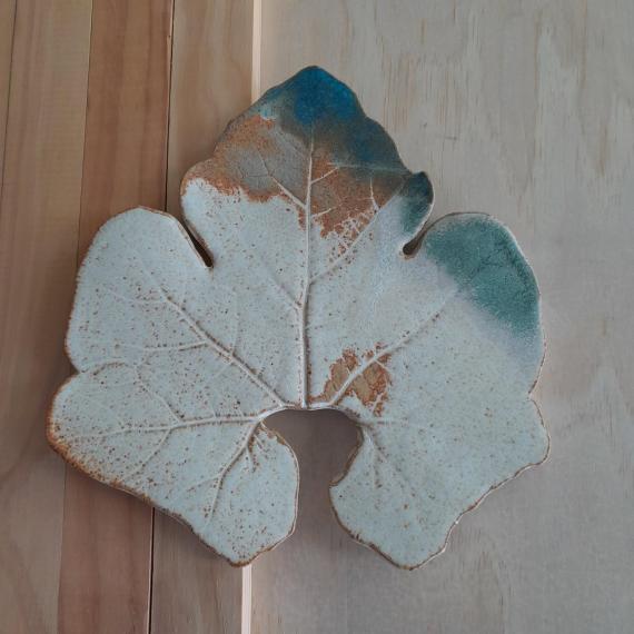 a close up of a ceramic leaf painted in greens and browns