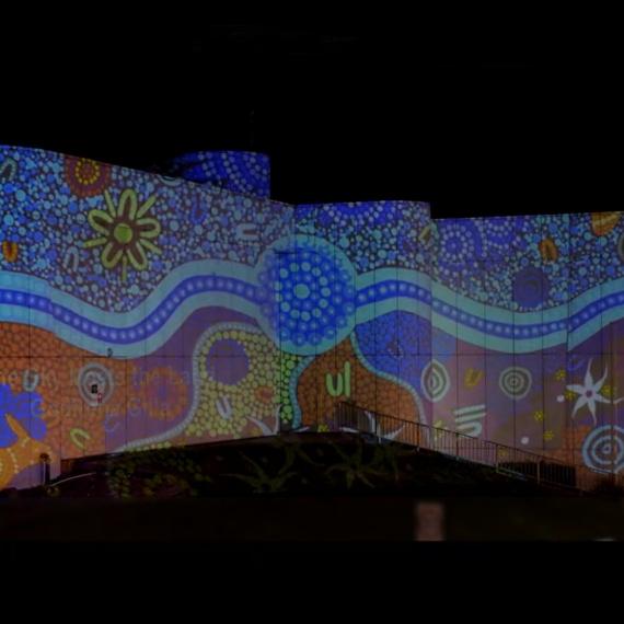an exterior shot of a building with colourful light projections featuring artwork 