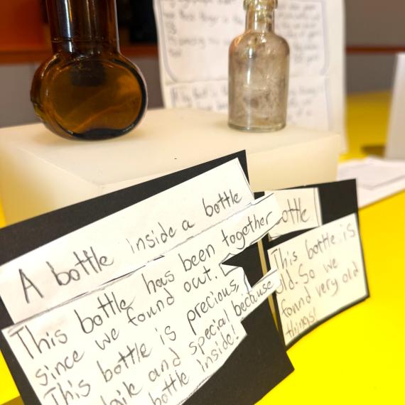bottle artefacts and handwritten descriptions displayed on a table