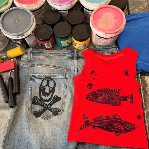 paint cans next to some clothing with prints on them from the paints