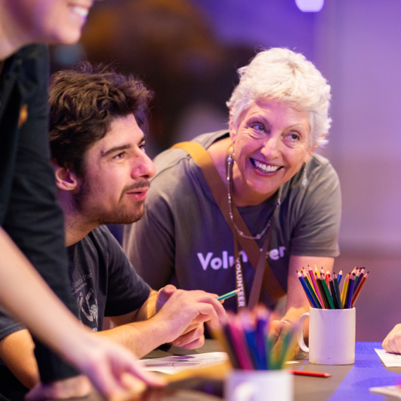 Museum Volunteer helping a person with disability seated at a table