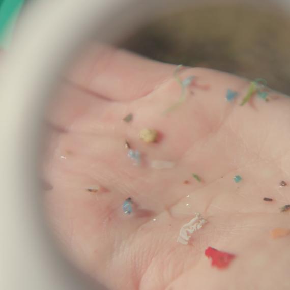 Palm of someone's hand displaying tiny pieces of multi-coloured plastic 