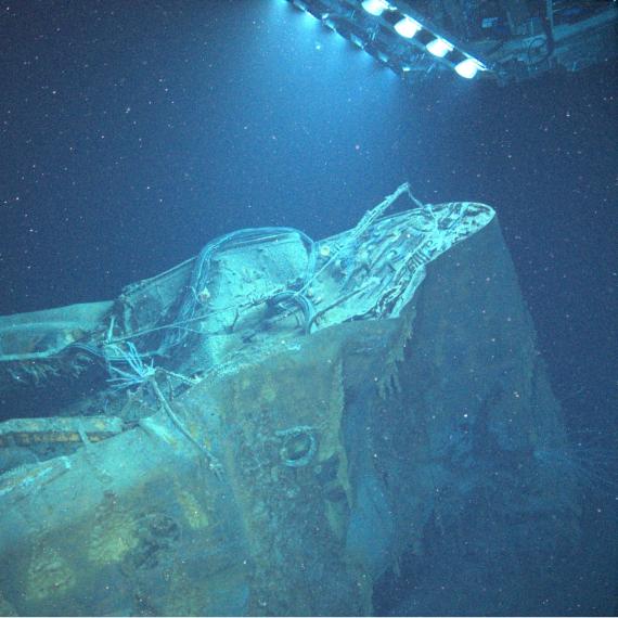 a shipwreck in the ocean with a remote operated vehicle shining a light on the wreck